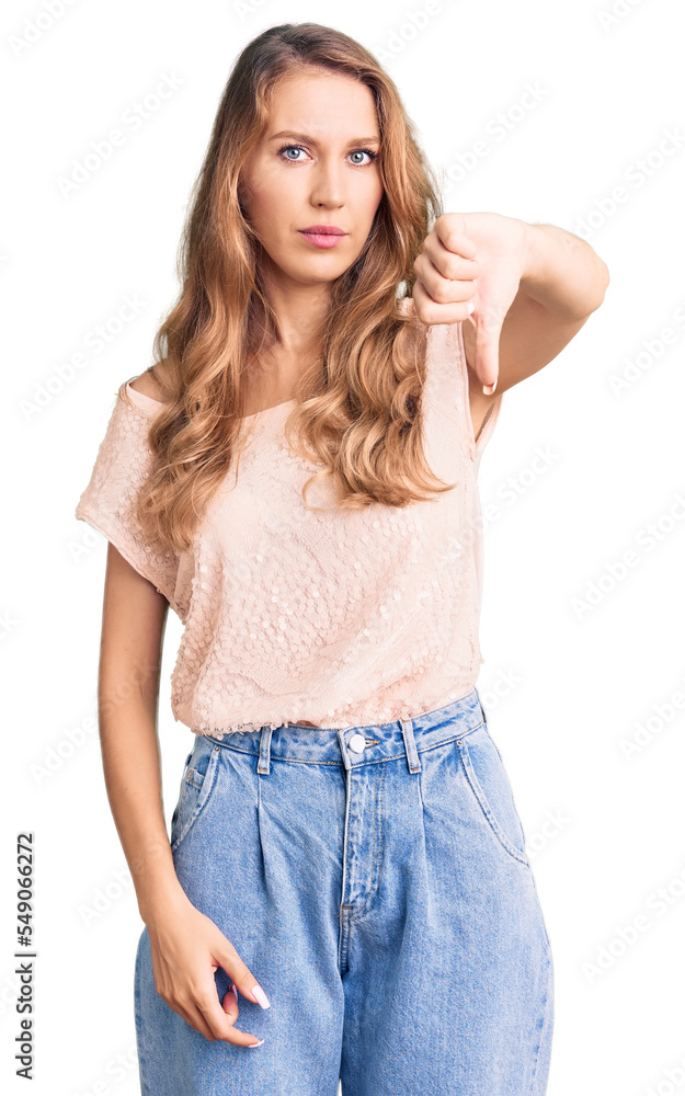 Young beautiful caucasian woman with blond hair wearing casual clothes looking unhappy and angry showing rejection and negative with thumbs down gesture. bad expression. Young beautiful caucasian woman with blond hair wearing casual clothes looking unhappy and angry showing rejection and negative with thumbs down gesture. bad expression.
