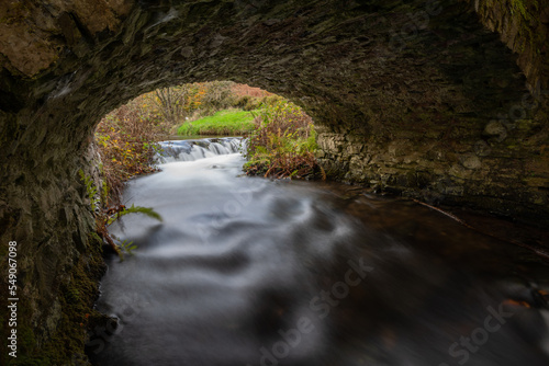 Long exposure of the Weir Water river flowing under Robbers Bridge in Exmoor National Park