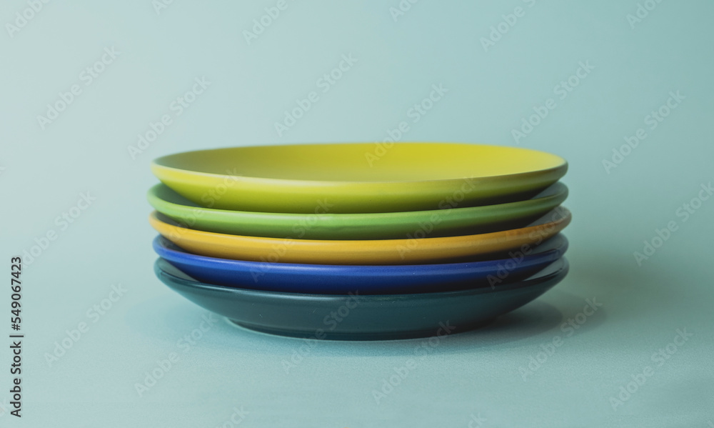 colored plates in a stack. saucers of different colors stand in a row colored plates in a stack. saucers of different colors stand in a row