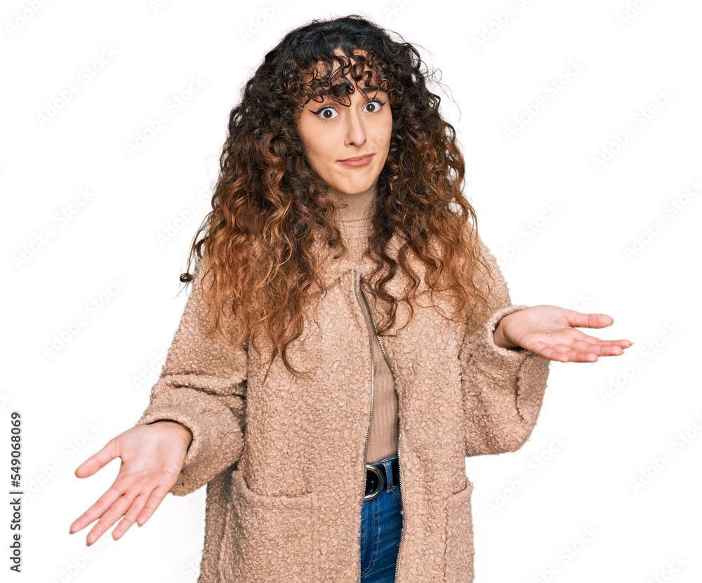 Young hispanic girl wearing winter clothes clueless and confused expression with arms and hands raised. doubt concept. Young hispanic girl wearing winter clothes clueless and confused expression with arms and hands raised. doubt concept.