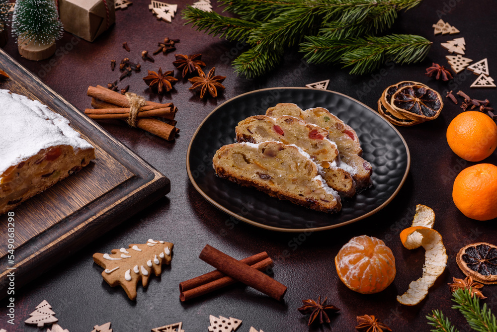Fototapeta premium Christmas pie stollen with marzipan, berries and nuts on a dark concrete background
