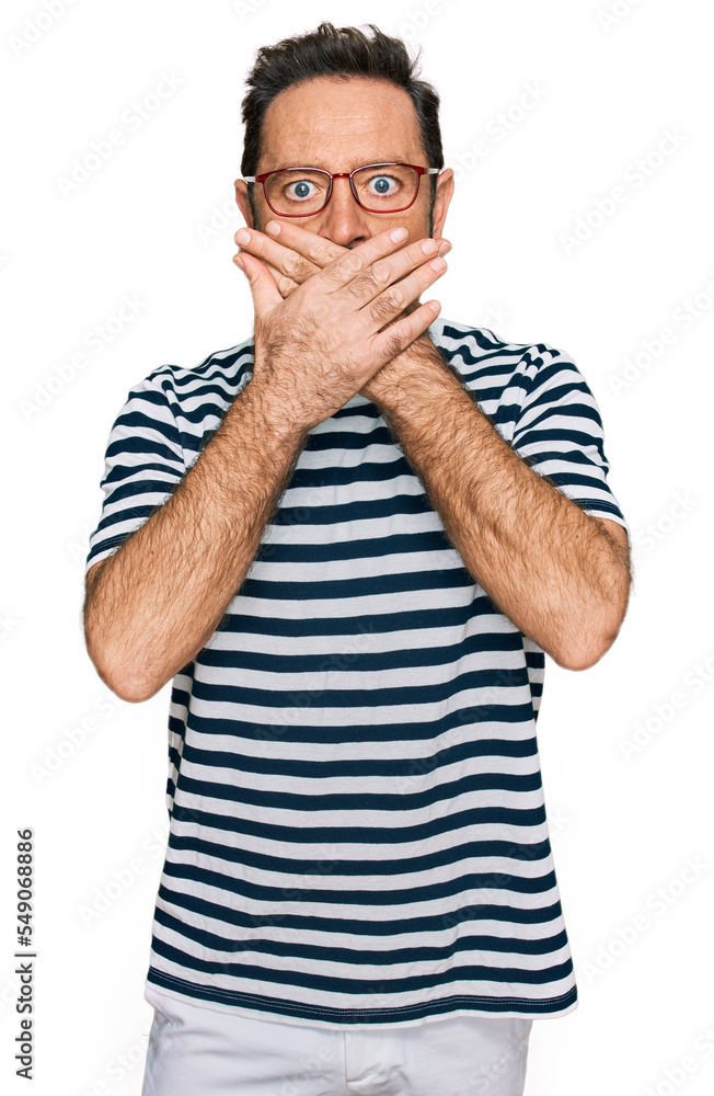 Middle age man wearing casual clothes and glasses shocked covering mouth with hands for mistake. secret concept. Middle age man wearing casual clothes and glasses shocked covering mouth with hands for mistake. secret concept.