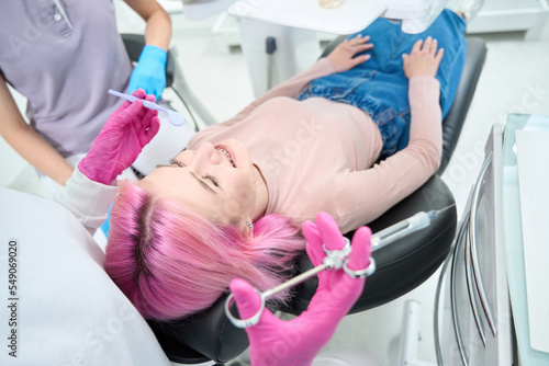 Woman in jeans and golf lies in a dental chair