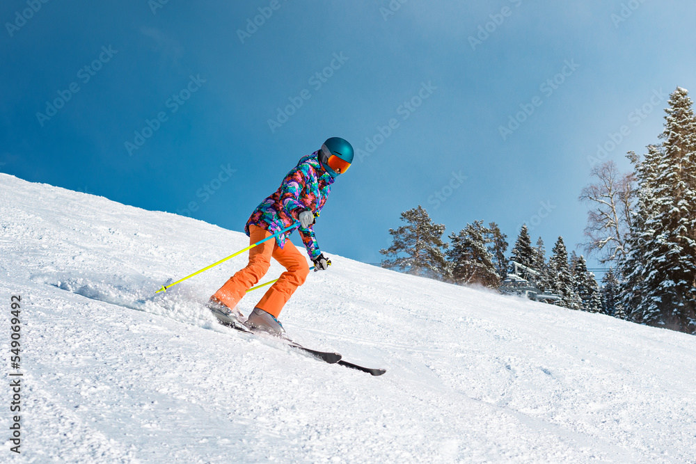 Female skier goes down the slope on a sunny day at a mountain resort.