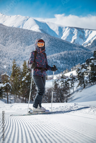Obraz na płótnie Female skier resting on the velvet slope on a sunny day at a mountain resort. w salonie