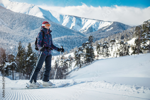 Obraz na płótnie Amateur female skier enjoying the view of the mountains on the velvet slope on a sunny day at a ski resort. w salonie