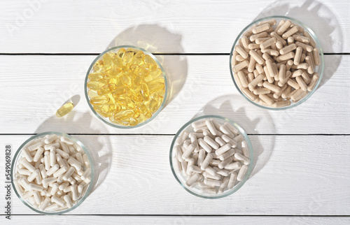 various supplement pills omega 3 and vitamins in petri dishes. healthcare support, top view, flat lay.