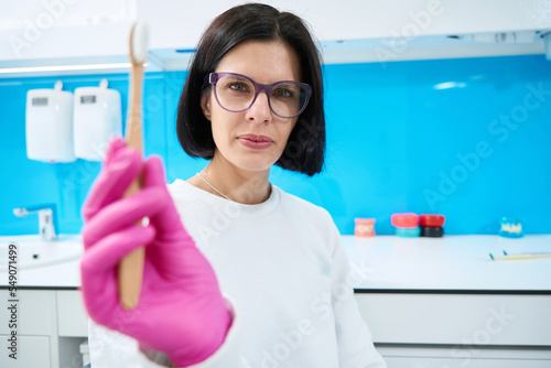 Free Download Woman dentist holds a wooden toothbrush in her hands - GFXLoad