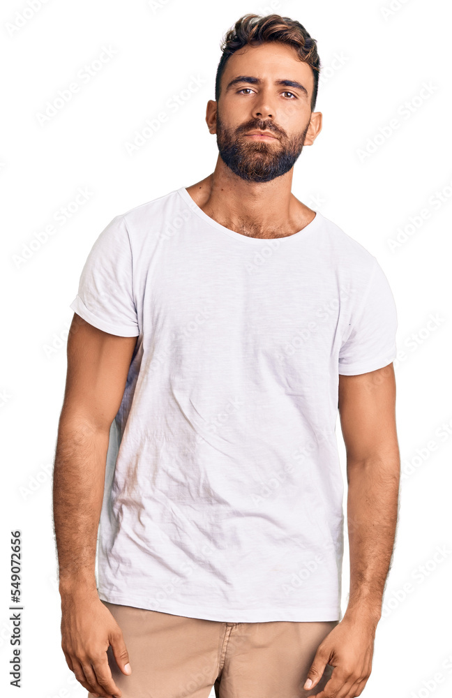 Young hispanic man wearing casual white tshirt relaxed with serious expression on face. simple and natural looking at the camera. Young hispanic man wearing casual white tshirt relaxed with serious expression on face. simple and natural looking at the camera.