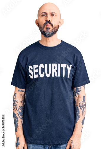 Young handsome man wearing security t shirt looking at the camera blowing a kiss on air being lovely and sexy. love expression.