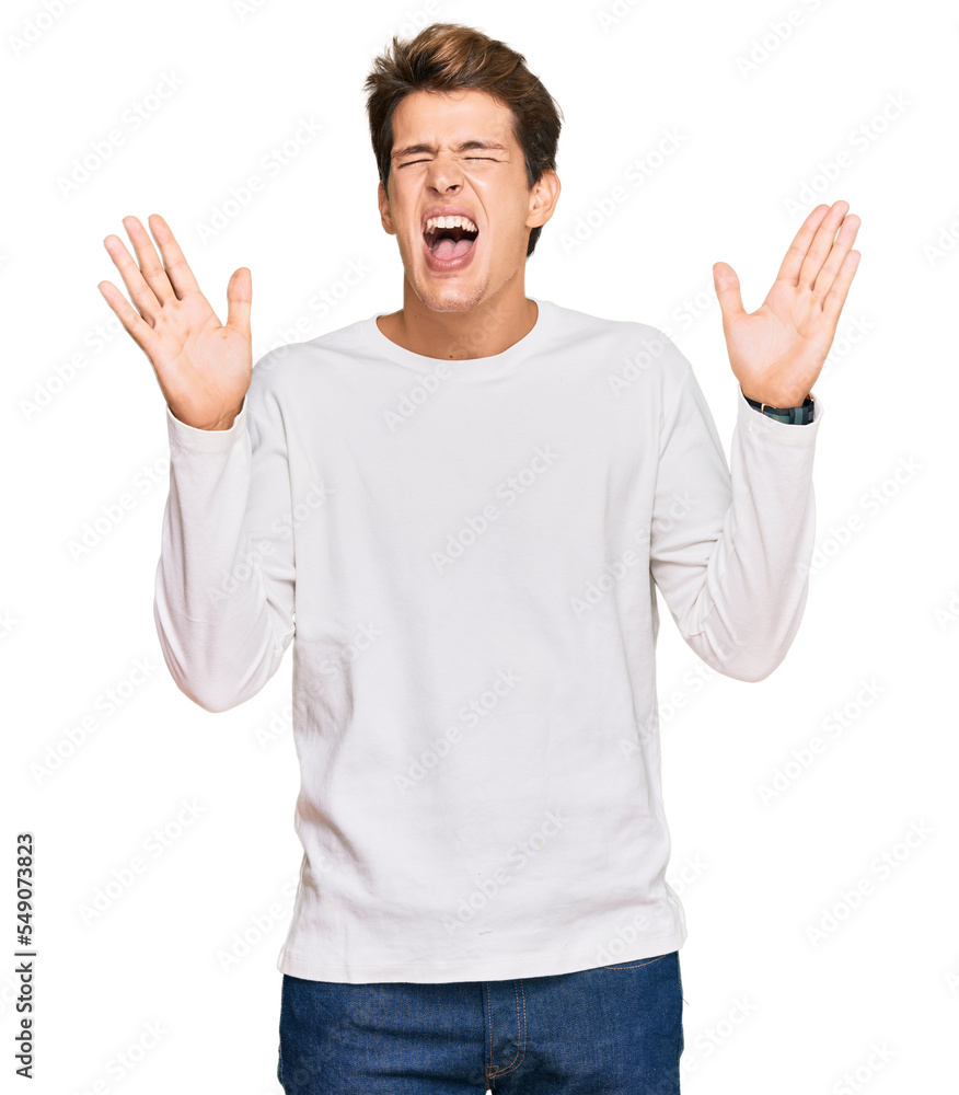 Fototapeta premium Handsome caucasian man wearing casual white sweater celebrating mad and crazy for success with arms raised and closed eyes screaming excited. winner concept