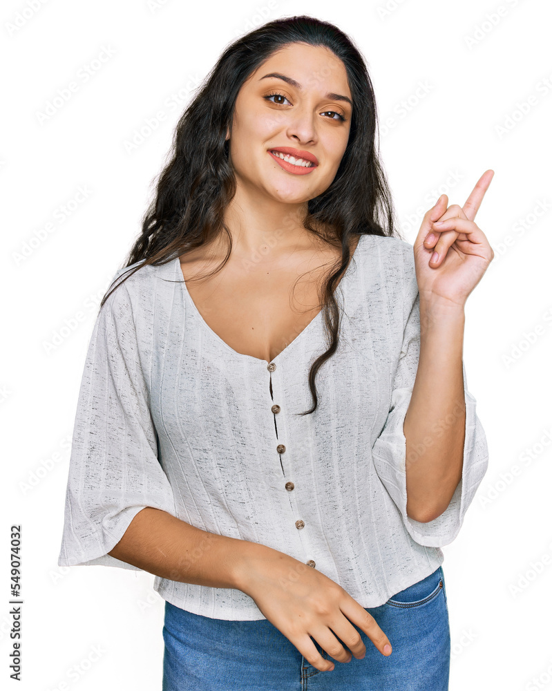 Brunette young woman wearing casual clothes with a big smile on face, pointing with hand and finger to the side looking at the camera. Brunette young woman wearing casual clothes with a big smile on face, pointing with hand and finger to the side looking at the camera.