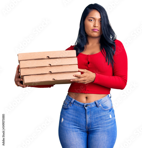 Fotografie Hispanic woman with long hair holding delivery pizza box thinking attitude and s