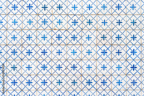 Fragment of building wall with white and blue ceramic wall tiles Azulejo Abstract decorative background textured ornate pattern. Traditional ornate Portuguese architecture 