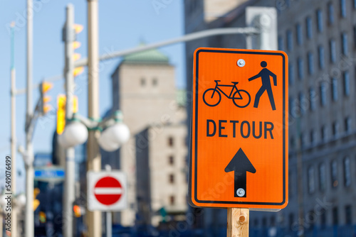 Orange detour sign for bikes and pedestrians. Closed way for bikes and walking people in downtown Ottawa, Canada photo