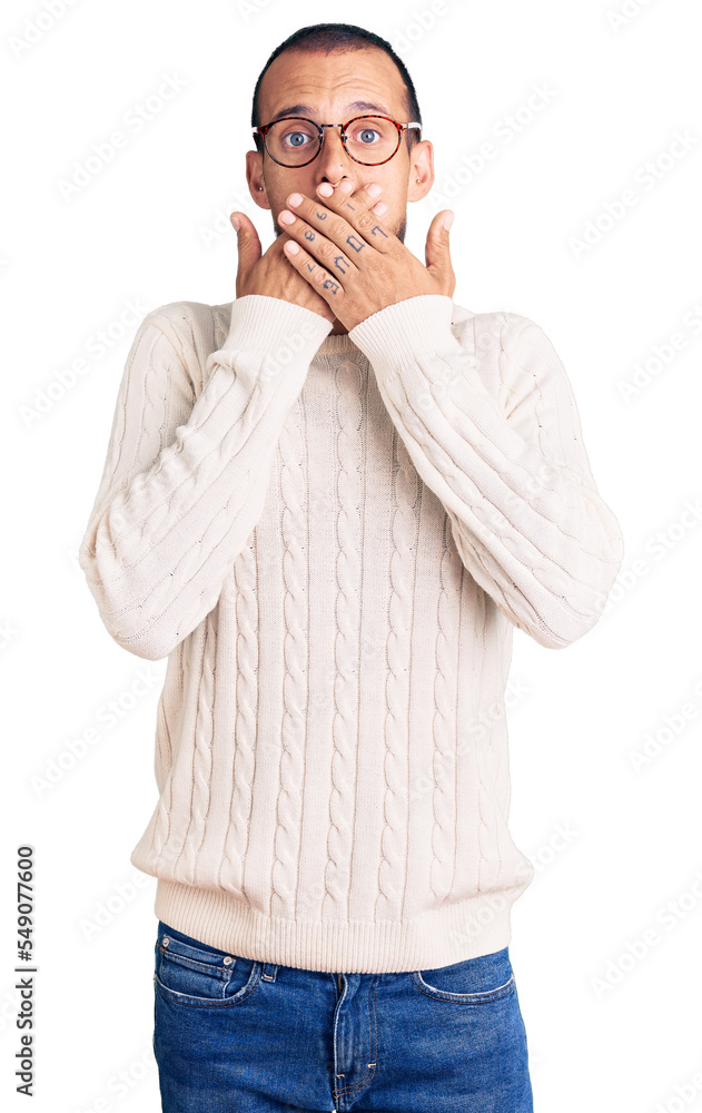 Young handsome man wearing casual clothes and glasses shocked covering mouth with hands for mistake. secret concept. Young handsome man wearing casual clothes and glasses shocked covering mouth with hands for mistake. secret concept.