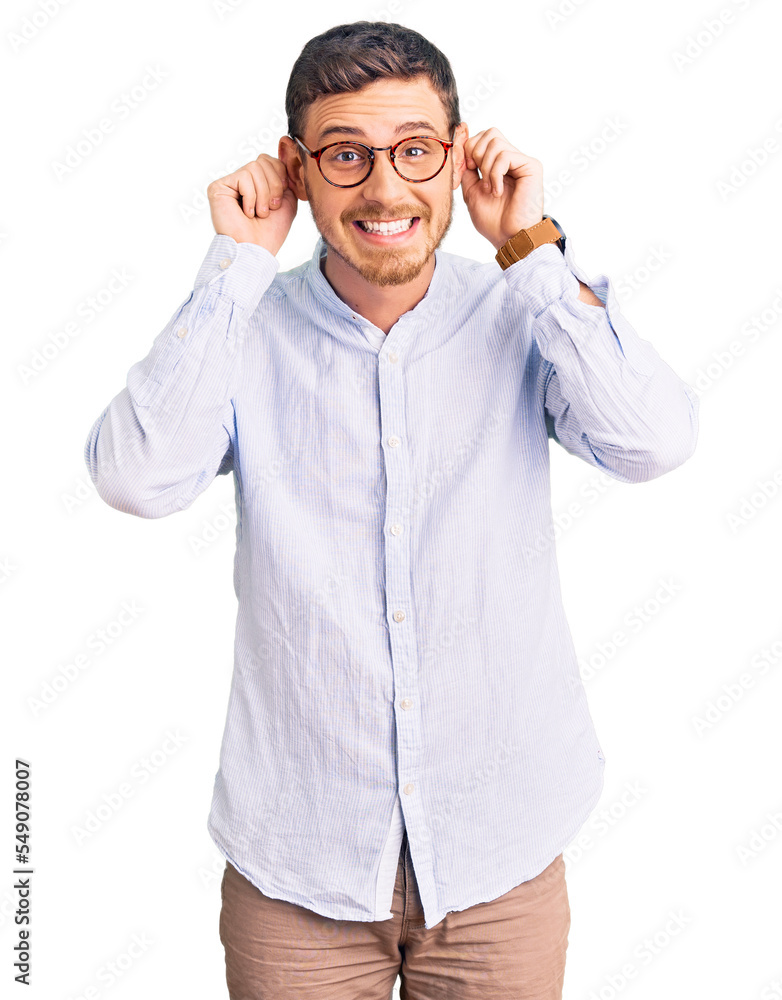 Fototapeta premium Handsome young man with bear wearing elegant business shirt and glasses smiling pulling ears with fingers, funny gesture. audition problem