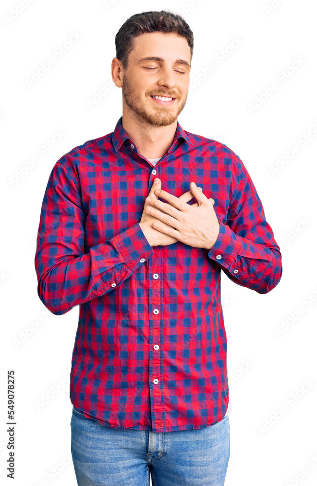 Handsome young man with bear wearing casual shirt smiling with hands on chest with closed eyes and grateful gesture on face. health concept. Handsome young man with bear wearing casual shirt smiling with hands on chest with closed eyes and grateful gesture on face. health concept.