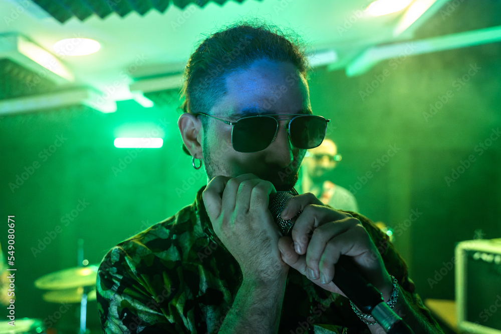 Man in sunglasses singing into microphone in studio Man in sunglasses singing into microphone in studio