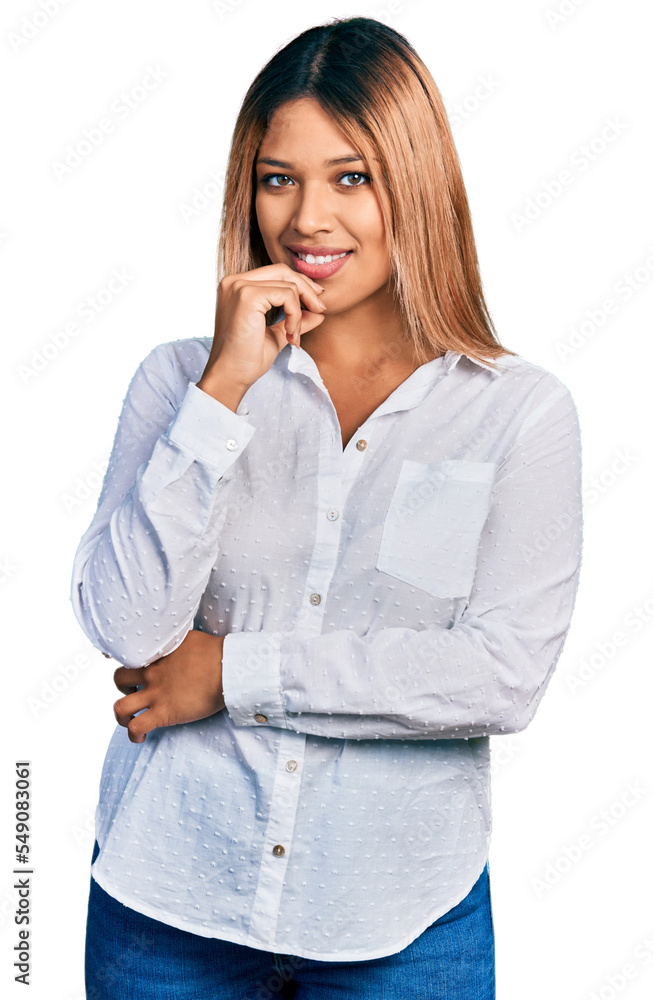 Young hispanic woman wearing casual white shirt looking confident at the camera with smile with crossed arms and hand raised on chin. thinking positive. Young hispanic woman wearing casual white shirt looking confident at the camera with smile with crossed arms and hand raised on chin. thinking positive.