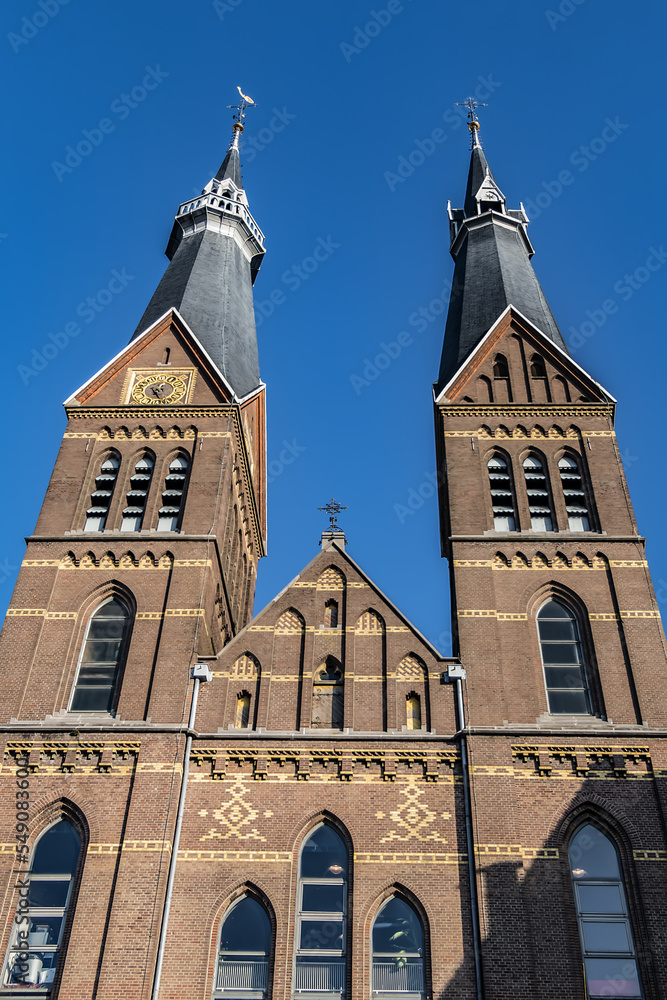 Obraz premium Neo-Gothic Post Horn Church (Posthoornkerk, 1863) with three slender towers on bustling Haarlemmerstraat - one of most important surviving XIX century churches. Sunset. Amsterdam, the Netherlands.