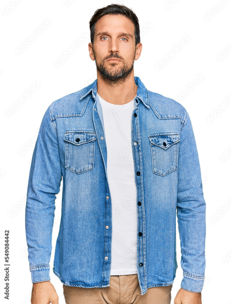 Young handsome man wearing casual denim jacket relaxed with serious expression on face. simple and natural looking at the camera. Young handsome man wearing casual denim jacket relaxed with serious expression on face. simple and natural looking at the camera.