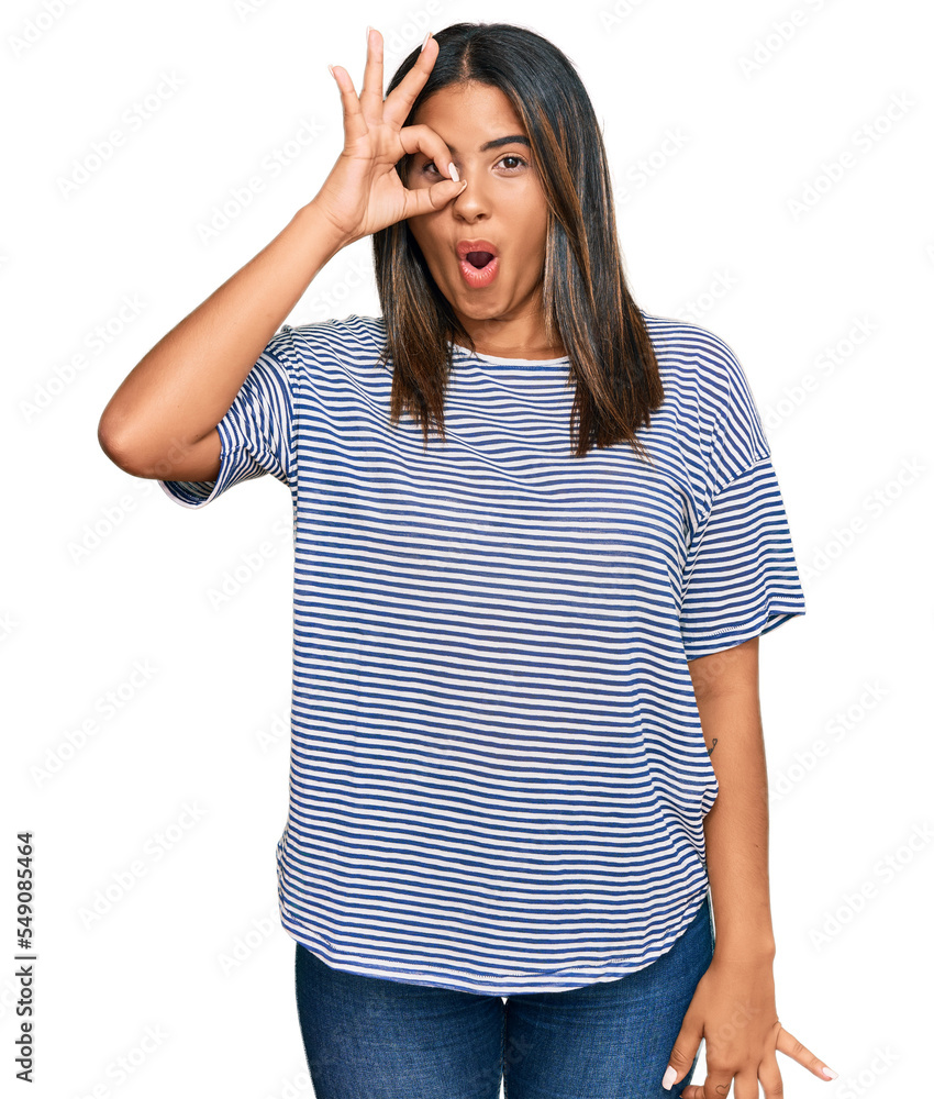 Young latin girl wearing casual clothes doing ok gesture shocked with surprised face, eye looking through fingers. unbelieving expression. Young latin girl wearing casual clothes doing ok gesture shocked with surprised face, eye looking through fingers. unbelieving expression.