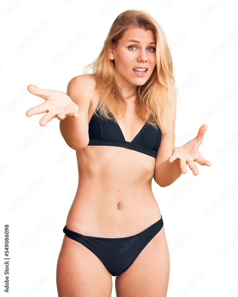 Young beautiful blonde woman wearing bikini smiling cheerful with open arms as friendly welcome, positive and confident greetings Young beautiful blonde woman wearing bikini smiling cheerful with open arms as friendly welcome, positive and confident greetings