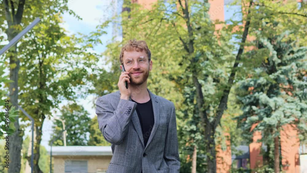 Cool stylish businessman talking on mobile phone outdoor. Cheerful handsome man in glasses having phone call at workplace in slow motion. Portrait of confident business man calling phone outside. Cool stylish businessman talking on mobile phone outdoor. Cheerful handsome man in glasses having phone call at workplace in slow motion. Portrait of confident business man calling phone outside.