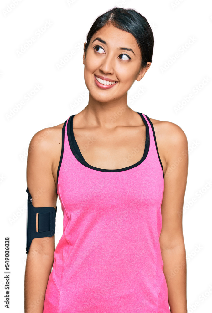 Beautiful asian young sport woman wearing sportswear and arm band smiling looking to the side and staring away thinking. Beautiful asian young sport woman wearing sportswear and arm band smiling looking to the side and staring away thinking.