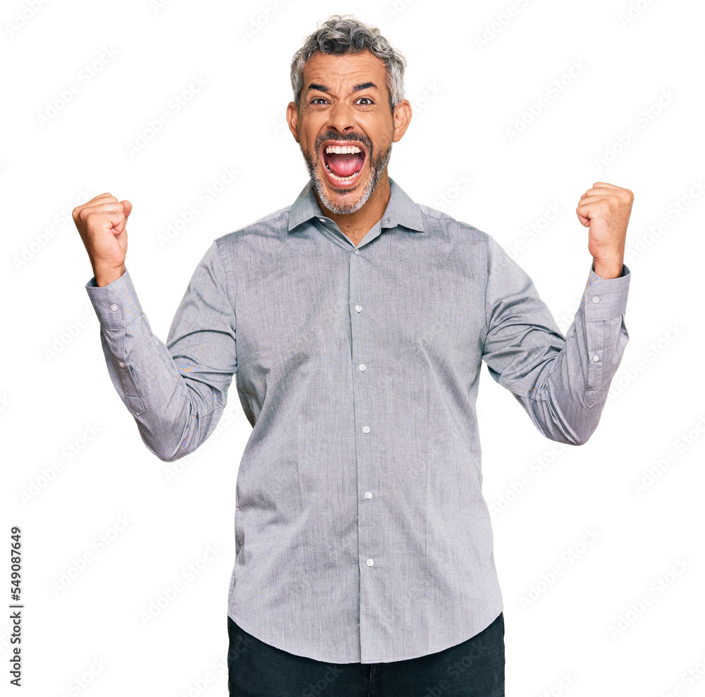 Middle age grey-haired man wearing casual clothes celebrating surprised and amazed for success with arms raised and open eyes. winner concept. Middle age grey-haired man wearing casual clothes celebrating surprised and amazed for success with arms raised and open eyes. winner concept.