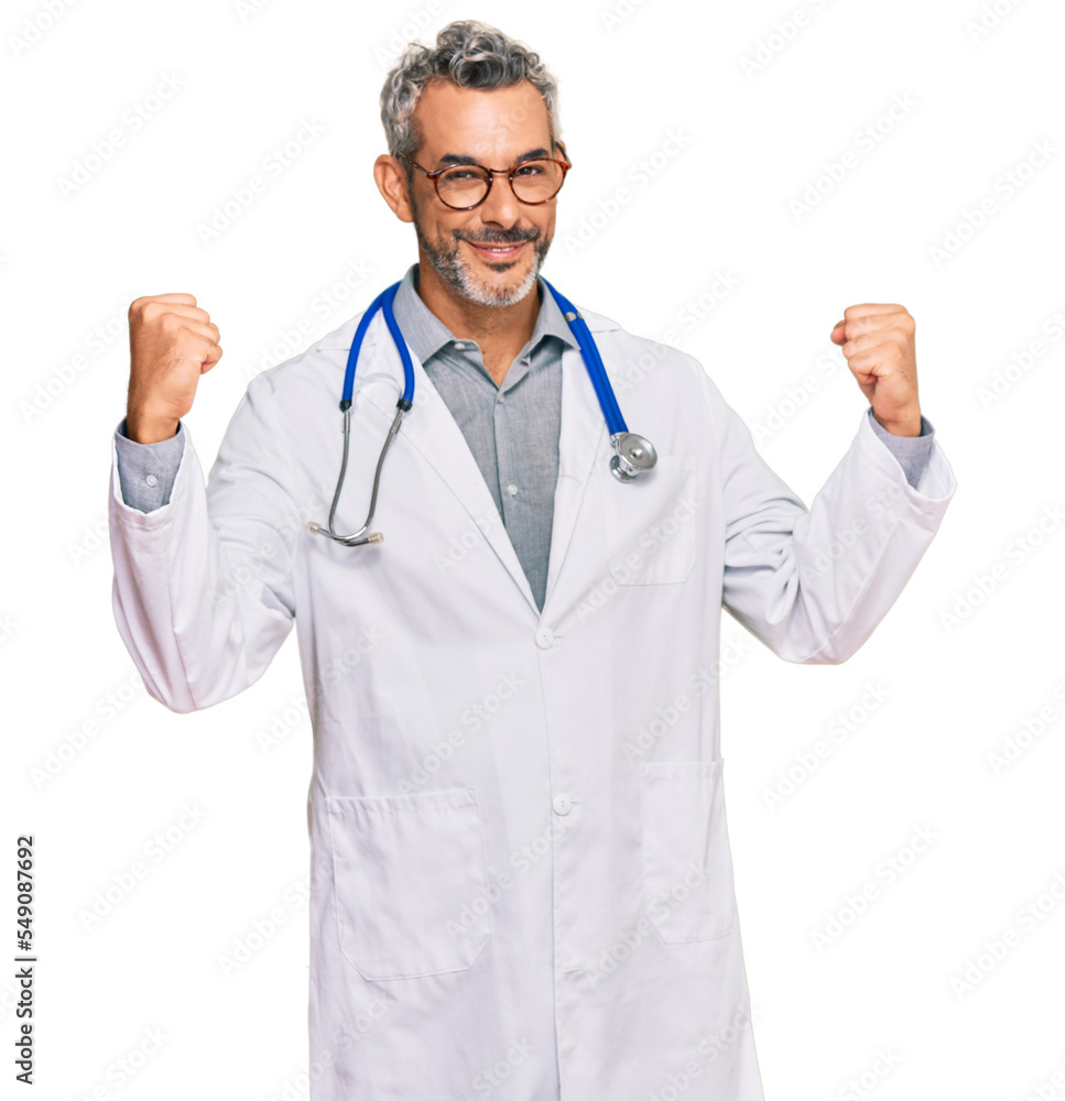 Middle age grey-haired man wearing doctor uniform and stethoscope screaming proud, celebrating victory and success very excited with raised arms Middle age grey-haired man wearing doctor uniform and stethoscope screaming proud, celebrating victory and success very excited with raised arms
