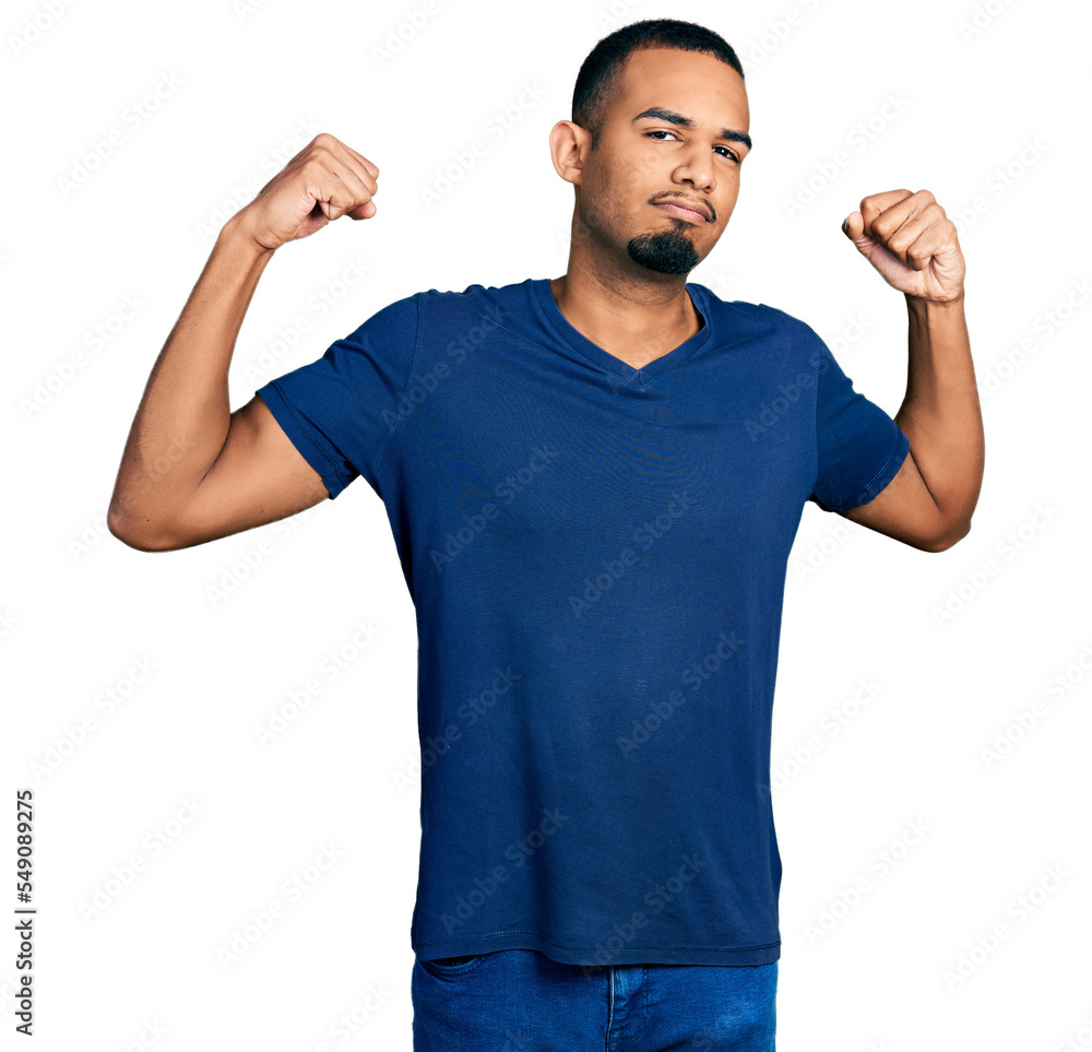 Young african american man wearing casual t shirt showing arms muscles smiling proud. fitness concept. Young african american man wearing casual t shirt showing arms muscles smiling proud. fitness concept.