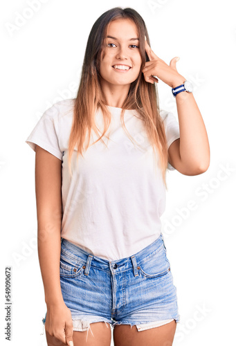 Beautiful caucasian woman wearing casual white tshirt smiling pointing to head with one finger, great idea or thought, good memory