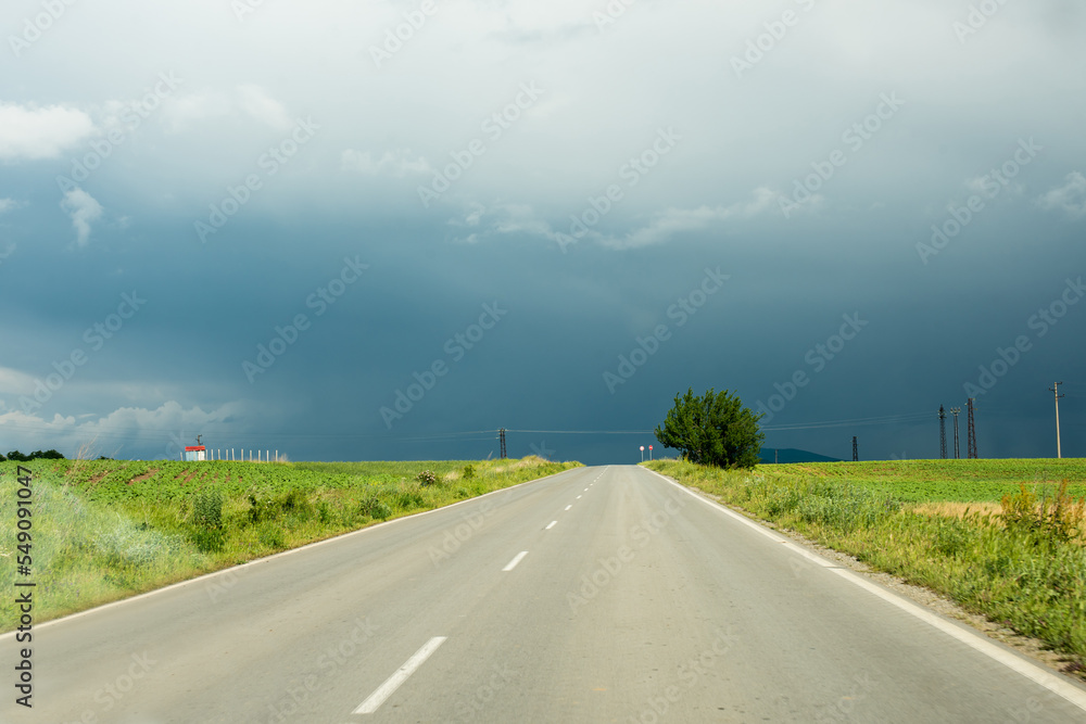 A view from a car driving down a road that leads into the center of a large storm.