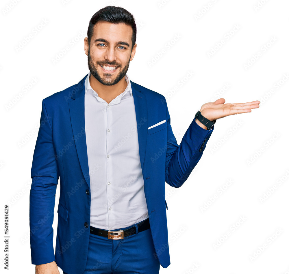 Young hispanic man wearing business jacket smiling cheerful presenting and pointing with palm of hand looking at the camera. Young hispanic man wearing business jacket smiling cheerful presenting and pointing with palm of hand looking at the camera.