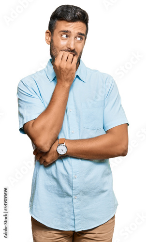 Handsome hispanic man wearing casual clothes looking stressed and nervous with hands on mouth biting nails. anxiety problem. photo