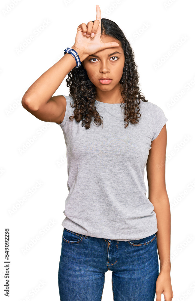 Fototapeta premium Young african american girl wearing casual clothes making fun of people with fingers on forehead doing loser gesture mocking and insulting.