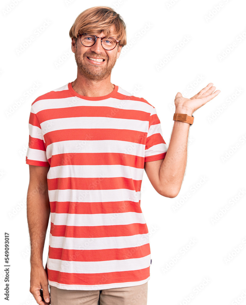 Handsome caucasian man with beard wearing casual clothes and glasses smiling cheerful presenting and pointing with palm of hand looking at the camera. Handsome caucasian man with beard wearing casual clothes and glasses smiling cheerful presenting and pointing with palm of hand looking at the camera.