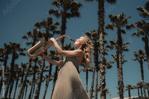 Canvas Print Girl with saxophones in nature among palm trees