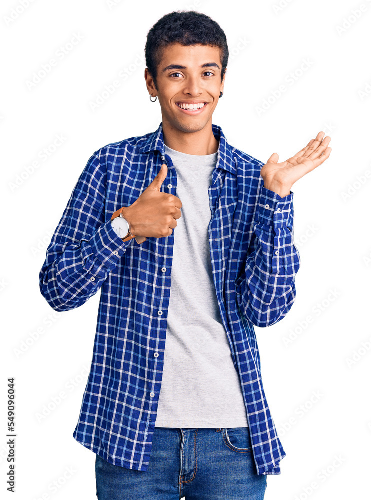 Young african amercian man wearing casual clothes showing palm hand and doing ok gesture with thumbs up, smiling happy and cheerful Young african amercian man wearing casual clothes showing palm hand and doing ok gesture with thumbs up, smiling happy and cheerful