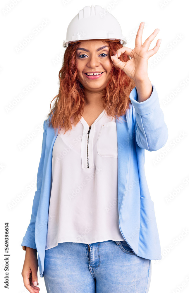 Young latin woman wearing architect hardhat smiling positive doing ok sign with hand and fingers. successful expression. Young latin woman wearing architect hardhat smiling positive doing ok sign with hand and fingers. successful expression.