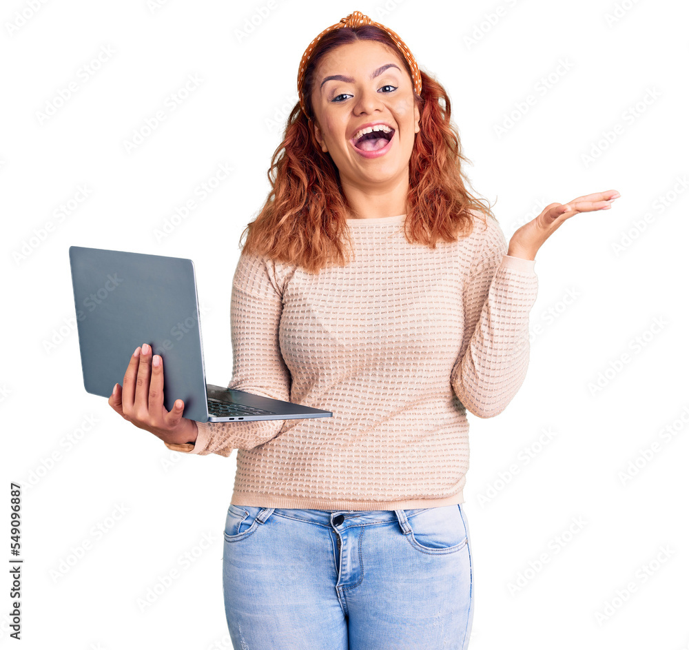Young latin woman holding laptop celebrating victory with happy smile and winner expression with raised hands Young latin woman holding laptop celebrating victory with happy smile and winner expression with raised hands
