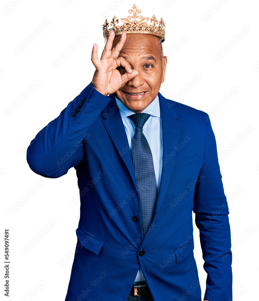 Hispanic middle age man wearing king crown smiling happy doing ok sign with hand on eye looking through fingers Hispanic middle age man wearing king crown smiling happy doing ok sign with hand on eye looking through fingers