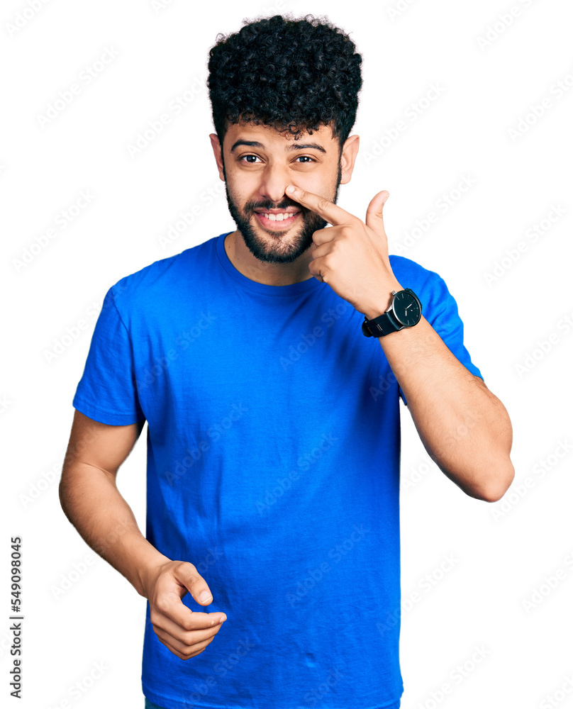 Young arab man with beard wearing casual blue t shirt pointing with hand finger to face and nose, smiling cheerful. beauty concept Young arab man with beard wearing casual blue t shirt pointing with hand finger to face and nose, smiling cheerful. beauty concept