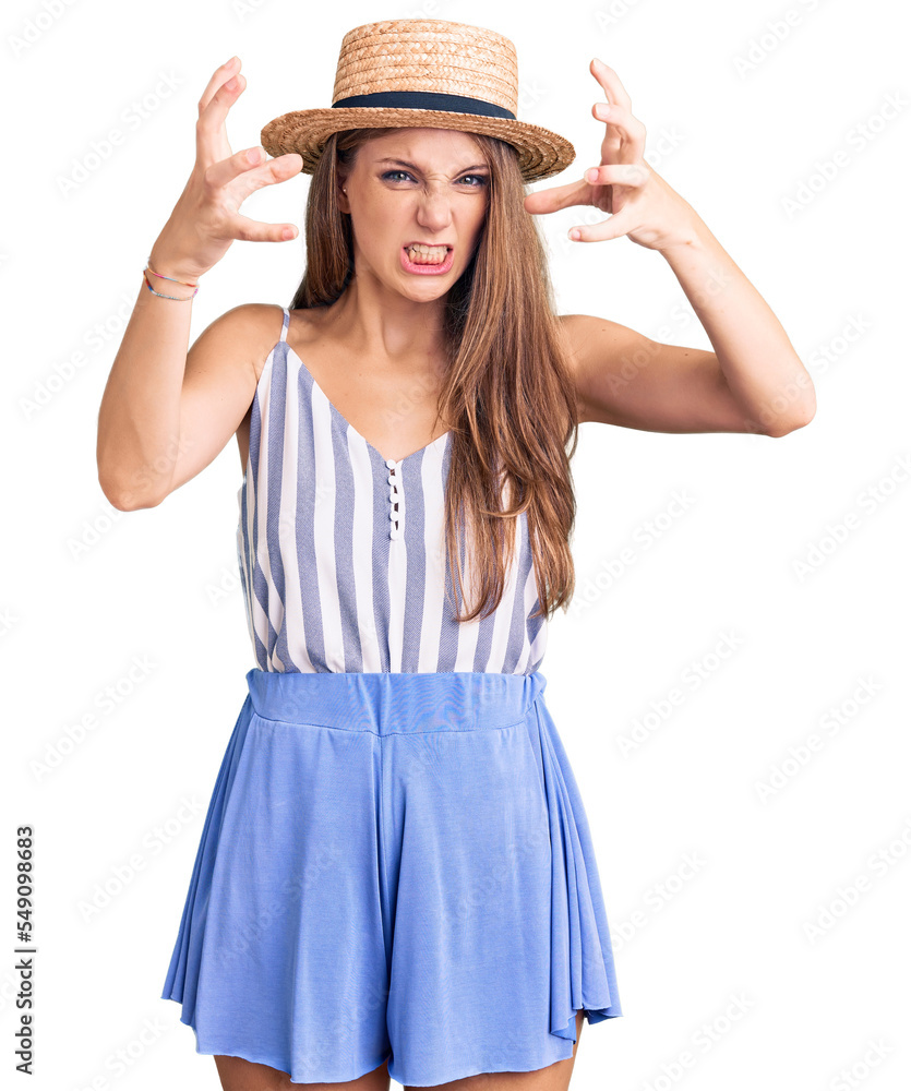 Young beautiful blonde woman wearing summer hat shouting frustrated with rage, hands trying to strangle, yelling mad Young beautiful blonde woman wearing summer hat shouting frustrated with rage, hands trying to strangle, yelling mad