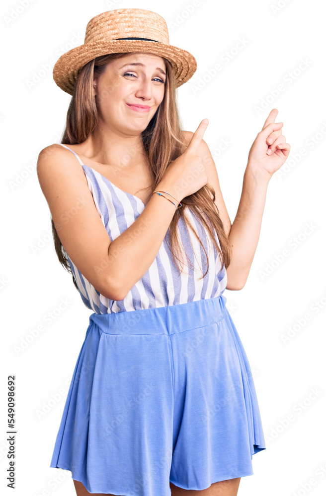 Young beautiful blonde woman wearing summer hat pointing aside worried and nervous with both hands, concerned and surprised expression Young beautiful blonde woman wearing summer hat pointing aside worried and nervous with both hands, concerned and surprised expression