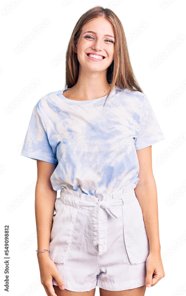 Young beautiful blonde woman wearing tye die tshirt looking positive and happy standing and smiling with a confident smile showing teeth Young beautiful blonde woman wearing tye die tshirt looking positive and happy standing and smiling with a confident smile showing teeth