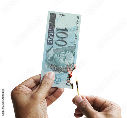 Burning money. Male hand setting a 100 reais bill on fire. Money from Brazil.  Transparent backgound 