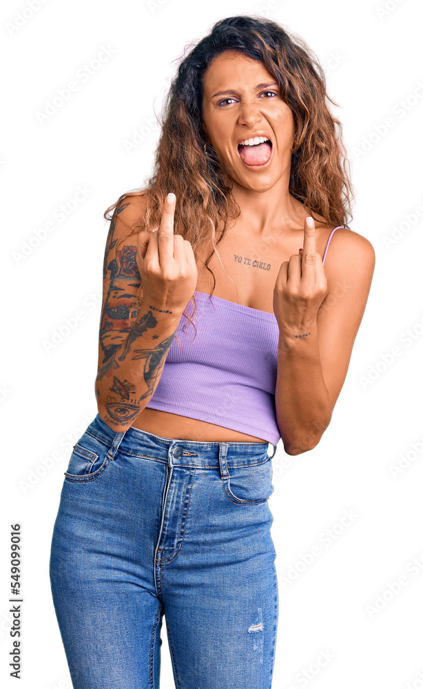Young hispanic woman with tattoo wearing casual clothes showing middle finger doing fuck you bad expression, provocation and rude attitude. screaming excited Young hispanic woman with tattoo wearing casual clothes showing middle finger doing fuck you bad expression, provocation and rude attitude. screaming excited